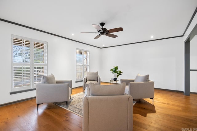 living room featuring hardwood / wood-style floors, crown molding, and ceiling fan