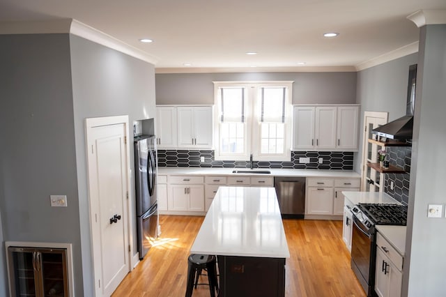 kitchen featuring sink, stainless steel appliances, a center island, wine cooler, and white cabinets