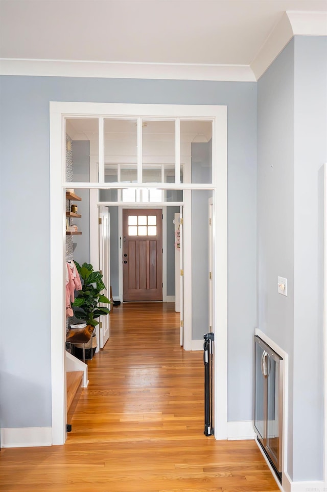 entryway with ornamental molding and hardwood / wood-style floors