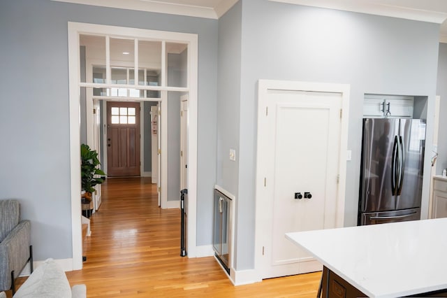 kitchen with ornamental molding, stainless steel refrigerator, and light wood-type flooring