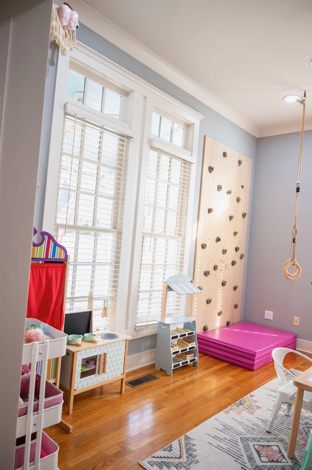 playroom with ornamental molding and hardwood / wood-style floors