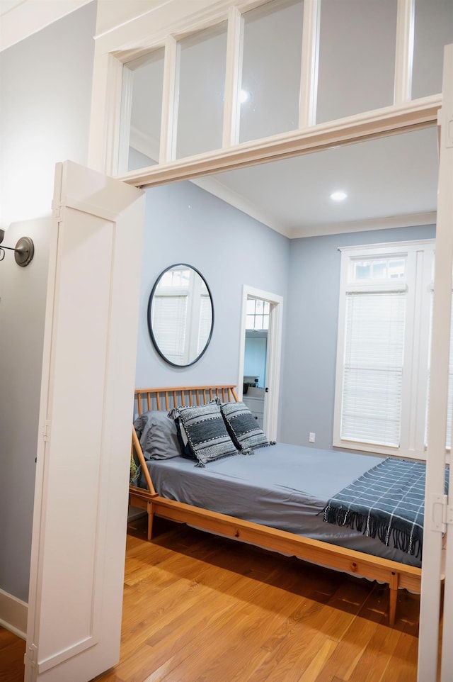 bedroom with crown molding, a towering ceiling, and light hardwood / wood-style floors