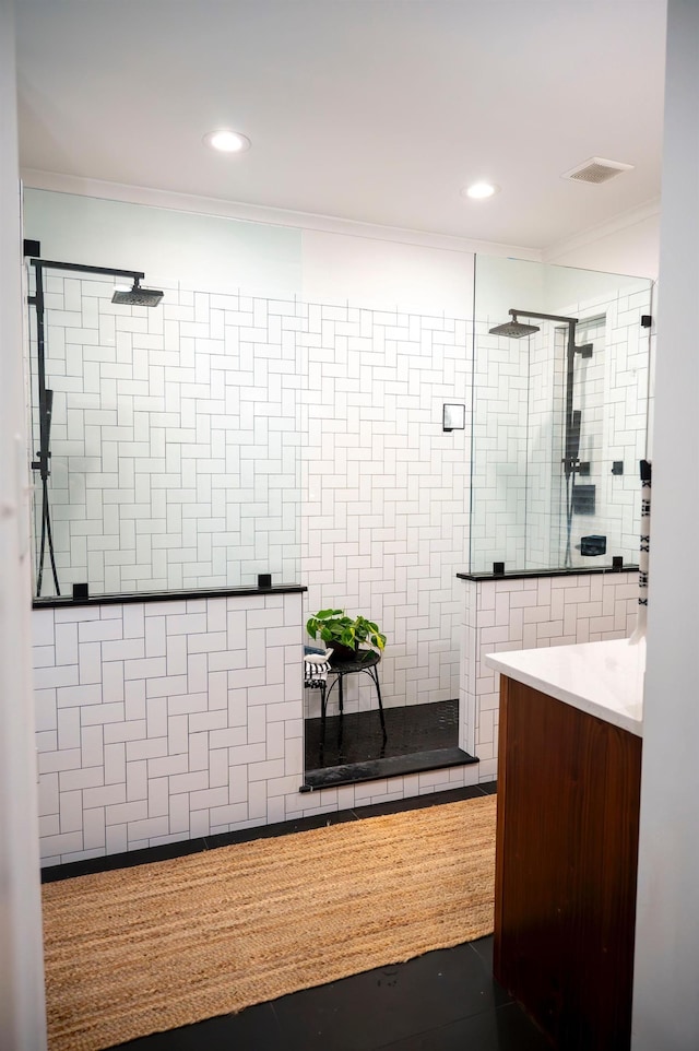 bathroom with vanity, crown molding, and a tile shower