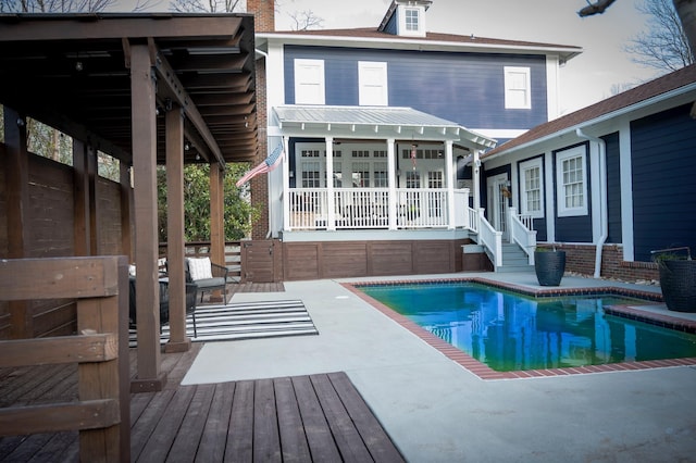 rear view of property featuring an outdoor structure and a pool side deck