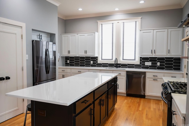 kitchen with sink, white cabinets, a center island, black appliances, and light hardwood / wood-style flooring