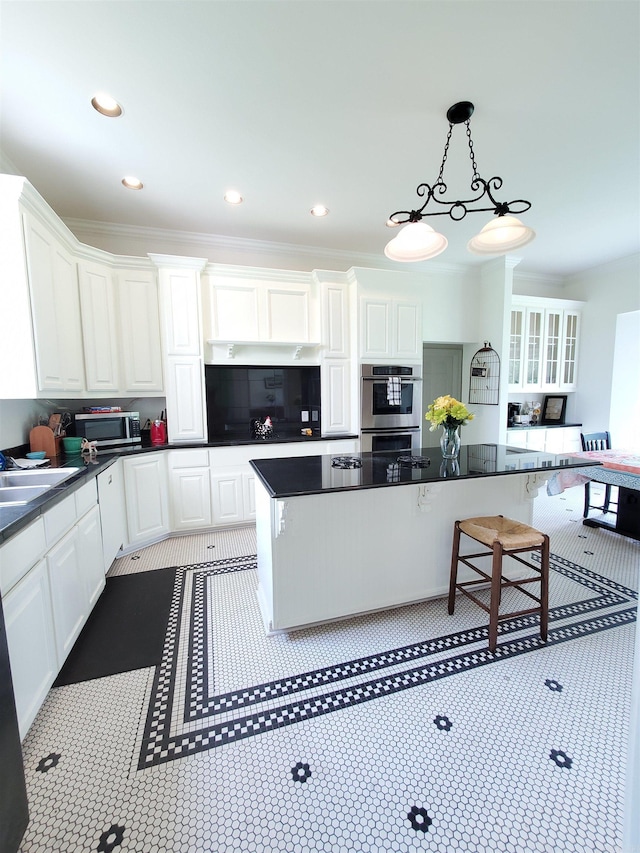 kitchen with appliances with stainless steel finishes, a kitchen bar, a center island, and white cabinets