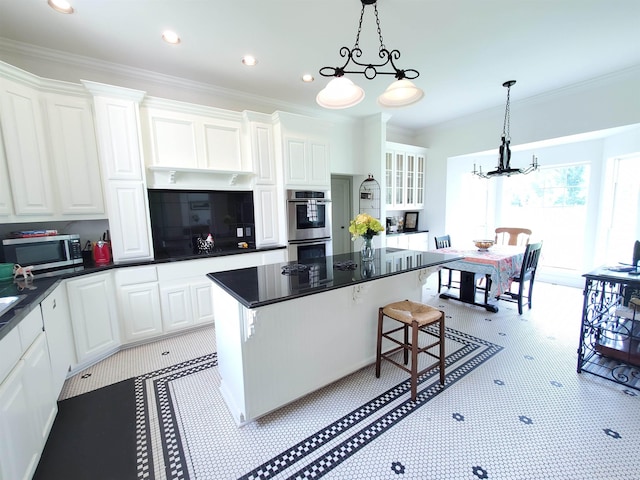 kitchen with pendant lighting, a center island, white cabinets, and appliances with stainless steel finishes