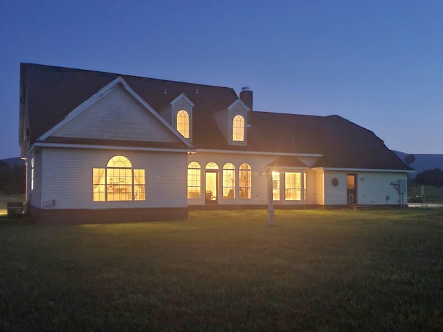 back house at dusk with french doors and a yard