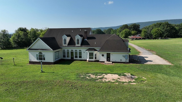 rear view of property featuring a mountain view and a lawn