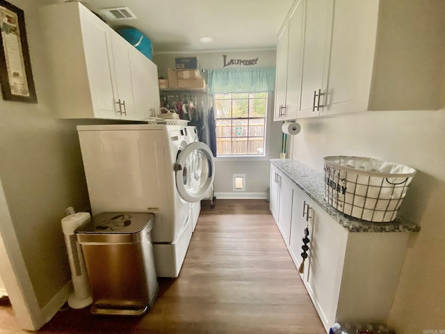 washroom featuring cabinets, light wood-type flooring, and washer and clothes dryer