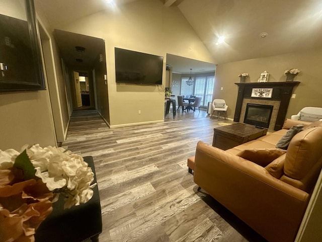 living room with a tiled fireplace, hardwood / wood-style floors, high vaulted ceiling, and beamed ceiling