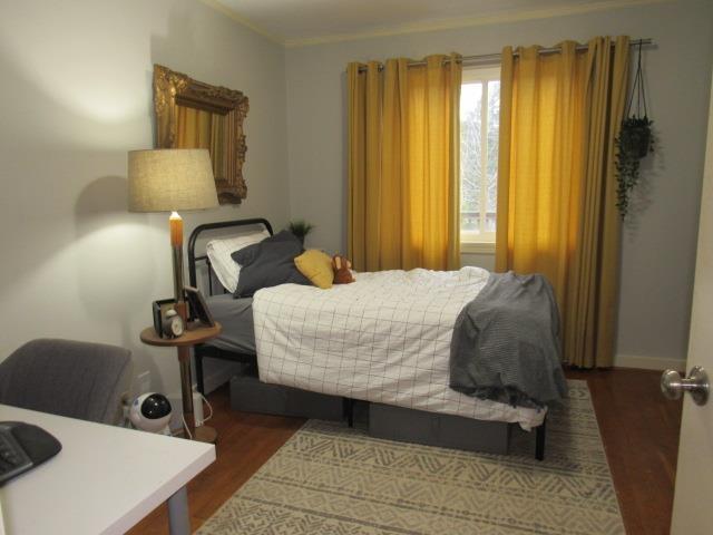 bedroom with ornamental molding and dark hardwood / wood-style floors