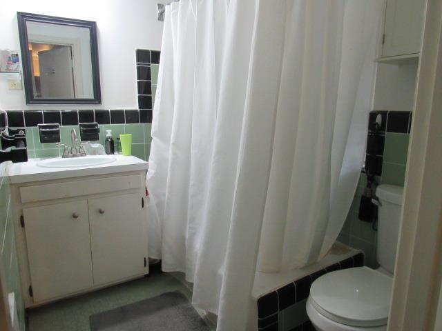 full bathroom with tile walls, vanity, decorative backsplash, toilet, and shower / bath combo with shower curtain