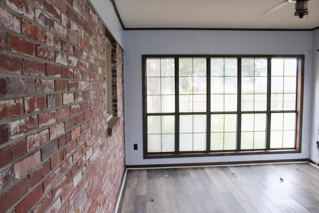 interior space with hardwood / wood-style flooring, ceiling fan, brick wall, and plenty of natural light