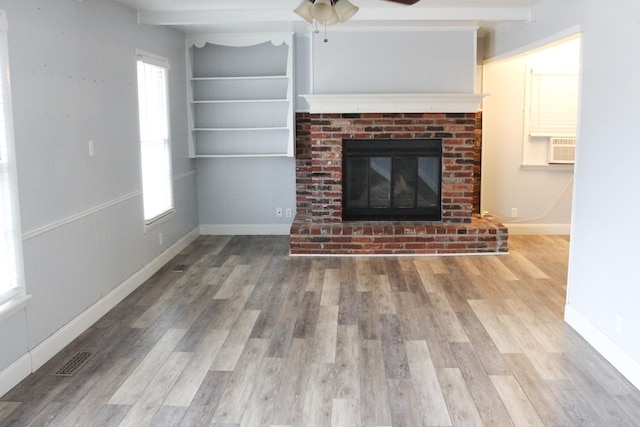 unfurnished living room with a fireplace, beam ceiling, hardwood / wood-style floors, and a wealth of natural light