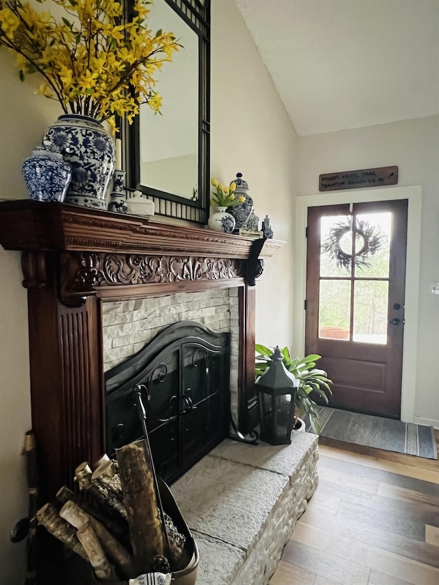 entryway featuring vaulted ceiling, light wood-type flooring, and a fireplace