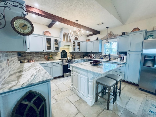 kitchen featuring premium range hood, appliances with stainless steel finishes, a kitchen island, hanging light fixtures, and light stone countertops