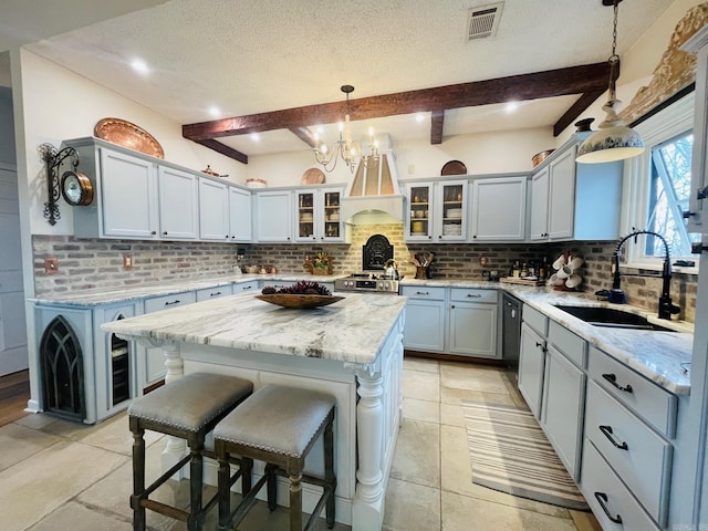 kitchen with sink, decorative light fixtures, a center island, beam ceiling, and backsplash