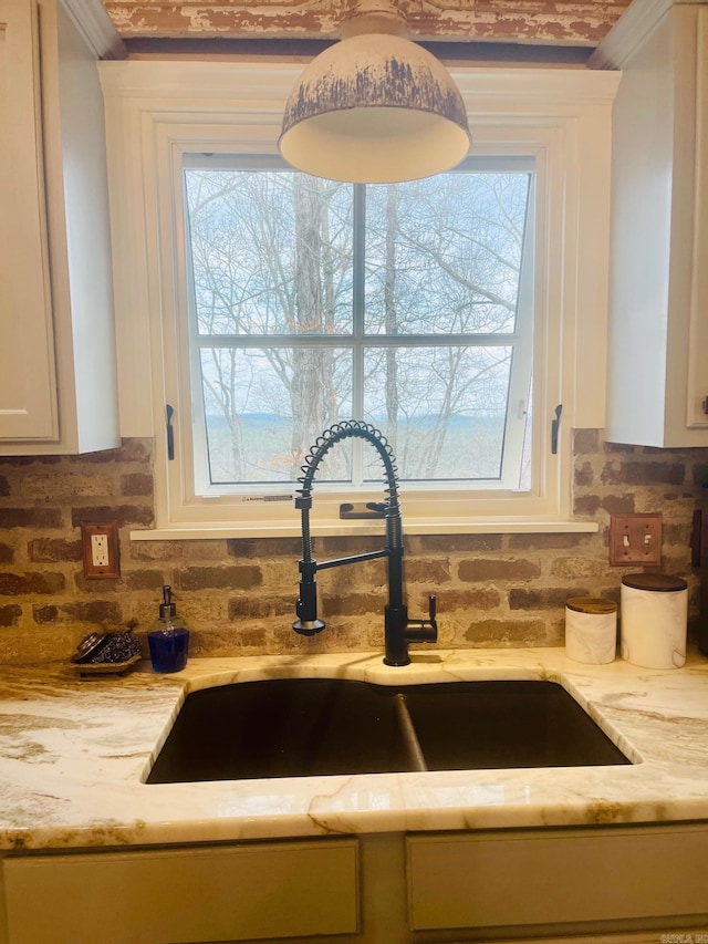 room details featuring sink, backsplash, white cabinets, and light stone counters