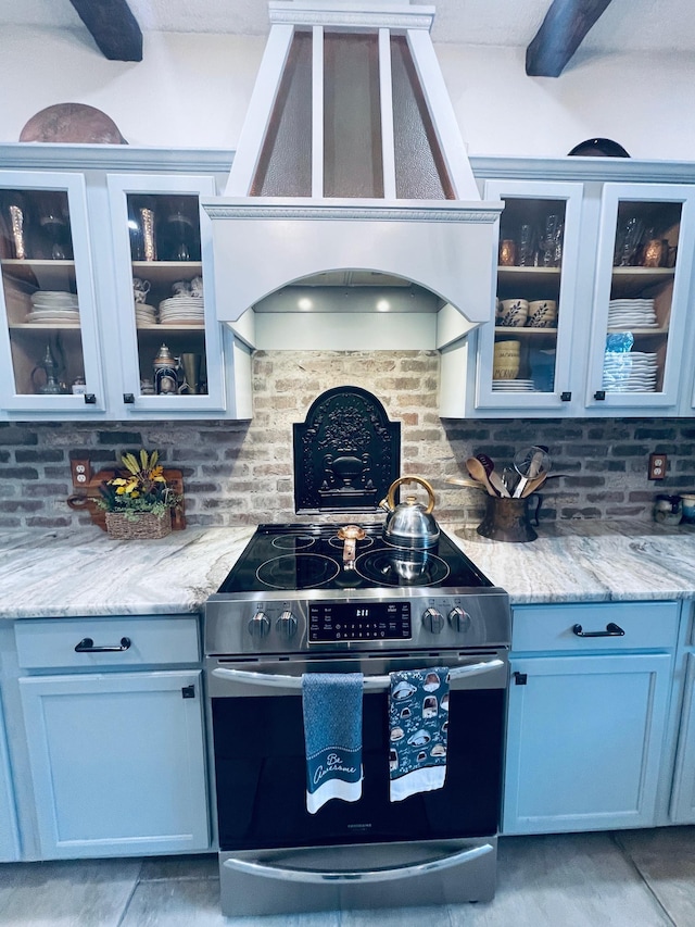 kitchen with electric stove, decorative backsplash, premium range hood, and light stone counters