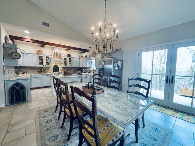 dining area featuring vaulted ceiling, sink, a chandelier, and french doors