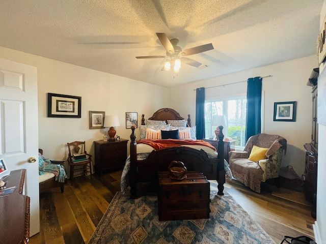 bedroom featuring ceiling fan, dark hardwood / wood-style floors, and a textured ceiling