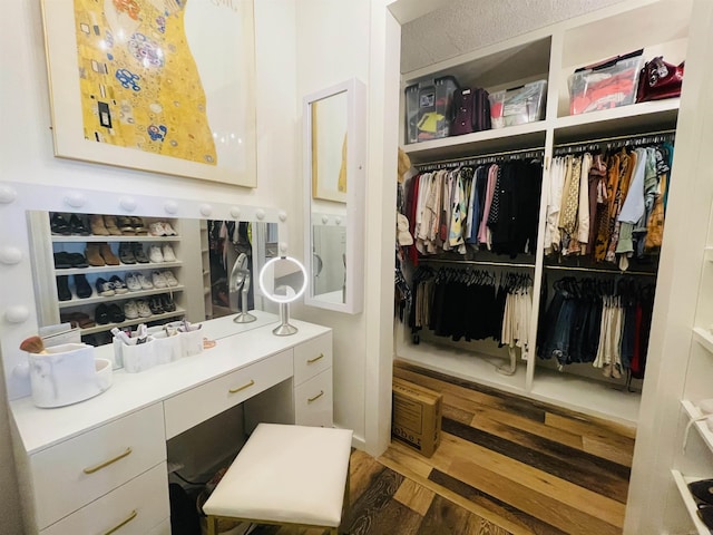 spacious closet featuring dark hardwood / wood-style floors and built in desk
