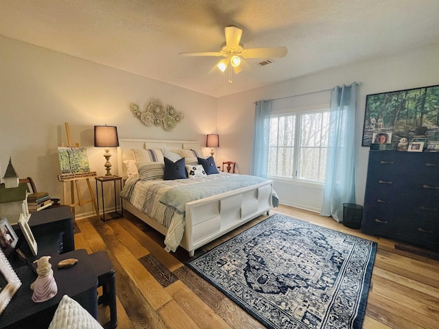 bedroom with hardwood / wood-style flooring, a textured ceiling, and ceiling fan