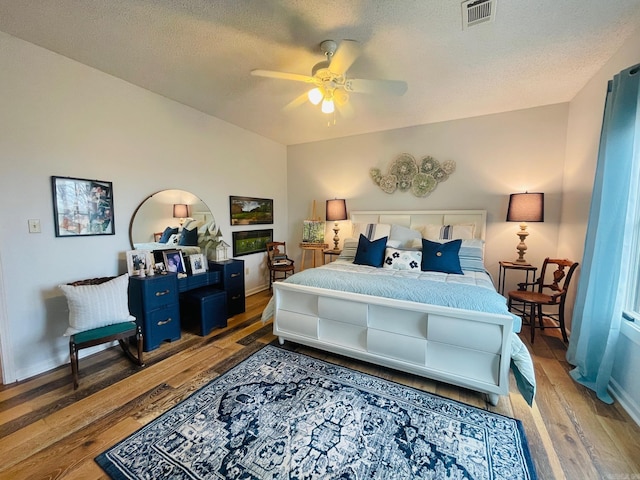 bedroom with ceiling fan, light hardwood / wood-style floors, and a textured ceiling