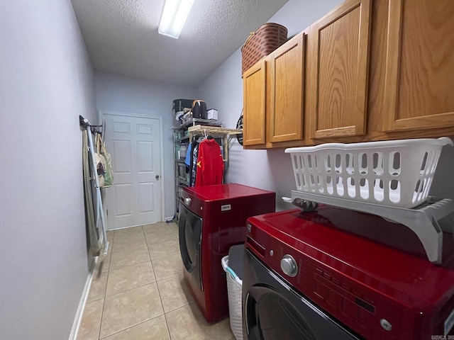 laundry room with cabinets, light tile patterned floors, a textured ceiling, and washer and clothes dryer