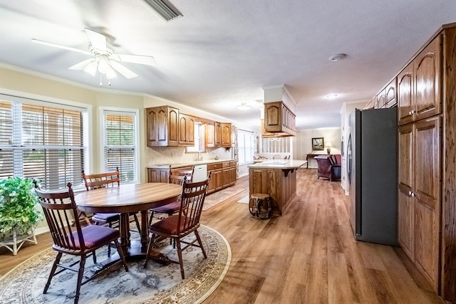 dining space featuring ornamental molding, ceiling fan, and light wood-type flooring