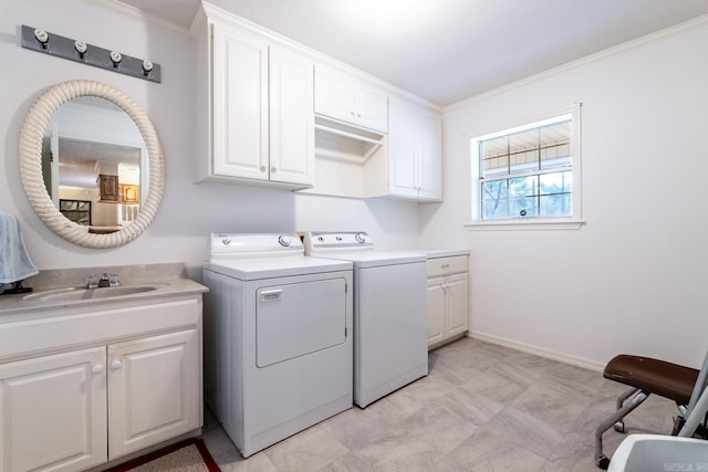 clothes washing area with sink, washer and clothes dryer, ornamental molding, and cabinets