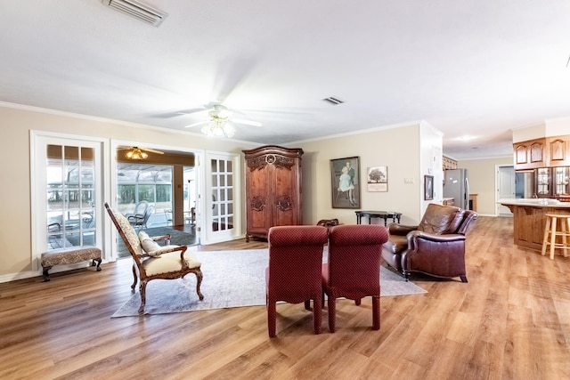 living room featuring crown molding, ceiling fan, and light wood-type flooring