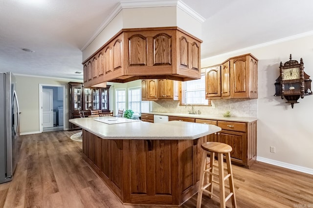 kitchen featuring a breakfast bar area, light hardwood / wood-style flooring, stainless steel refrigerator, ornamental molding, and white dishwasher