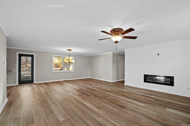 unfurnished living room featuring crown molding, ceiling fan with notable chandelier, a large fireplace, and hardwood / wood-style floors