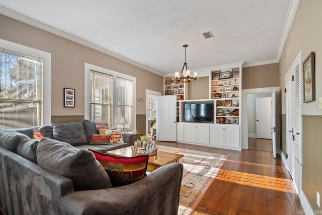 living room with an inviting chandelier, dark wood-type flooring, a wealth of natural light, and ornamental molding