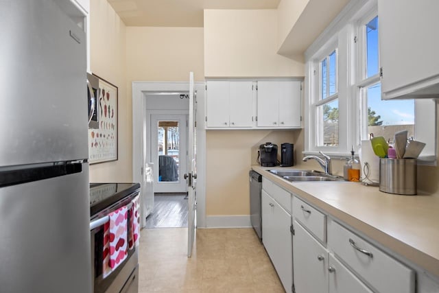 kitchen with white cabinetry, stainless steel appliances, sink, and light tile patterned floors