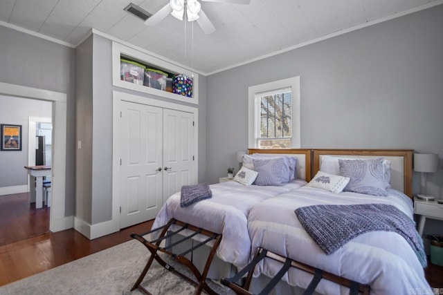 bedroom featuring dark wood-type flooring, ornamental molding, a closet, and ceiling fan