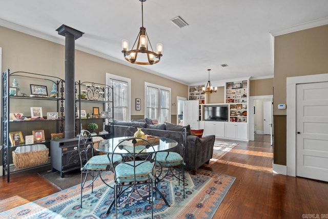 living room featuring crown molding, a wood stove, dark wood-type flooring, and an inviting chandelier