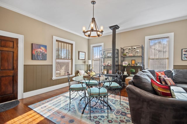 dining space featuring hardwood / wood-style flooring, ornamental molding, an inviting chandelier, and a wood stove