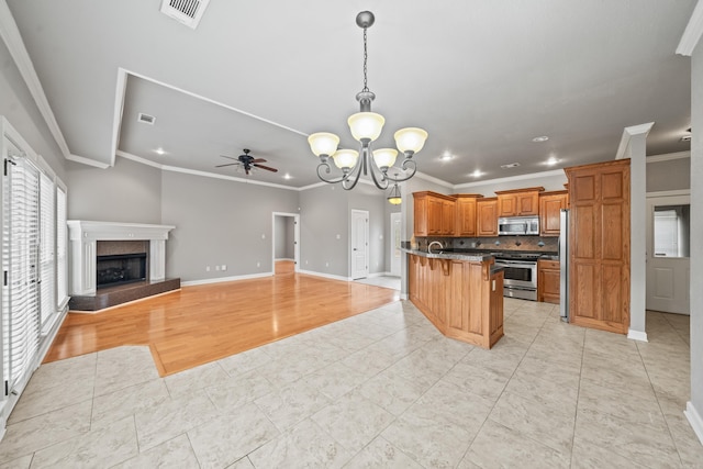 kitchen with a fireplace, a kitchen breakfast bar, decorative backsplash, light hardwood / wood-style floors, and stainless steel appliances