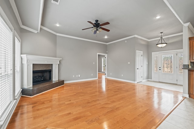 unfurnished living room with ceiling fan, light wood-type flooring, crown molding, and a high end fireplace