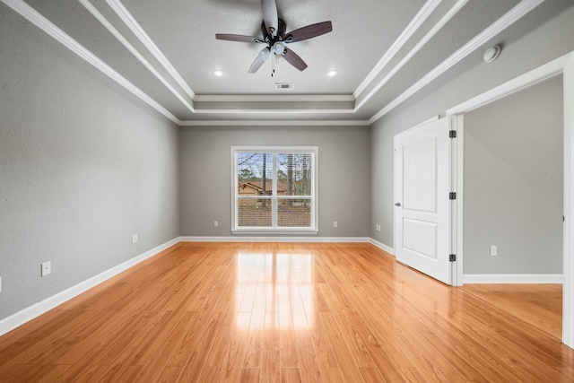 spare room with light hardwood / wood-style flooring, ornamental molding, a raised ceiling, and ceiling fan