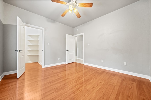 unfurnished bedroom with ceiling fan, a spacious closet, light hardwood / wood-style floors, and a closet