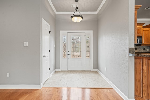 foyer entrance with crown molding and light hardwood / wood-style floors