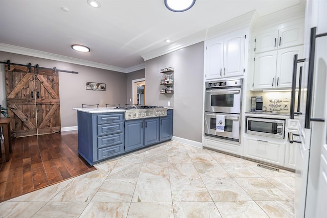 kitchen with blue cabinetry, white cabinetry, kitchen peninsula, stainless steel appliances, and a barn door