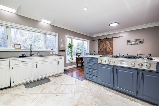 kitchen with stainless steel gas stovetop, white cabinetry, a barn door, and sink