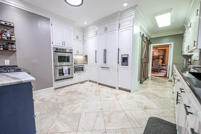 kitchen featuring crown molding, stainless steel appliances, a barn door, and white cabinets