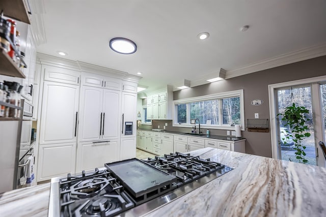 kitchen featuring sink, white cabinetry, crown molding, dark stone counters, and stainless steel appliances