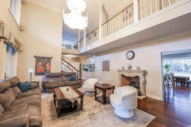 living room with an inviting chandelier, hardwood / wood-style floors, ornamental molding, and a high ceiling